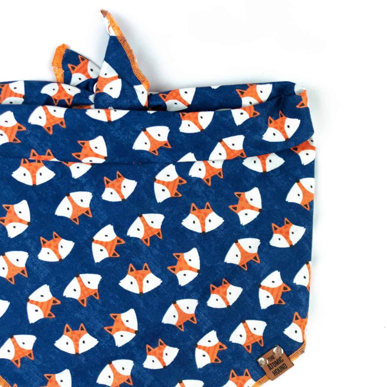 Navy blue dog bandana with orange and white fox print and orange hem